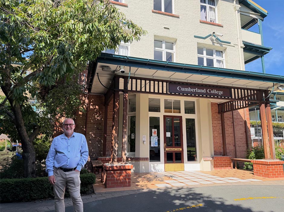 A man stands in front of Cumberland College.