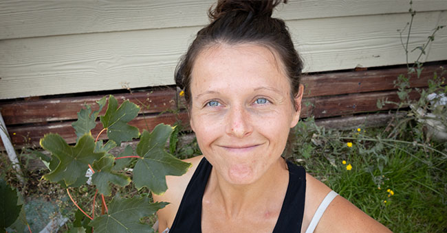 A woman looking up at the camera holding some sycamore leaves 