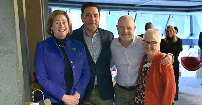 Four people pose for a photo at an event.