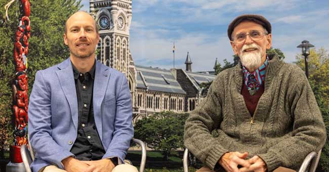 two men seated in front of an image of the University clocktower and Pou