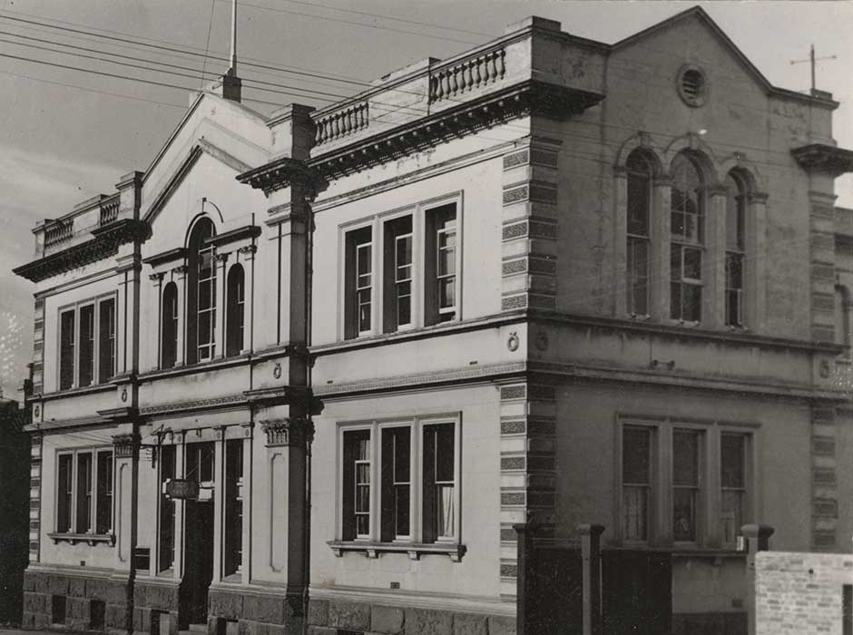 A black and white photo of an old two story building 