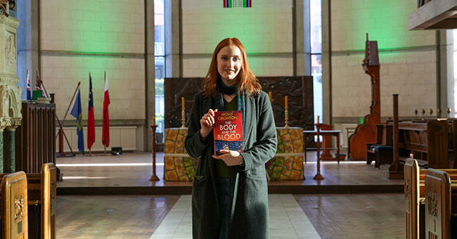 Author Molly Crighton pictured holding her book inside St Paul's Cathedral.
