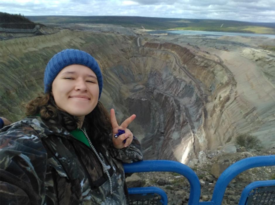 A woman is pictured in front of a large mine.
