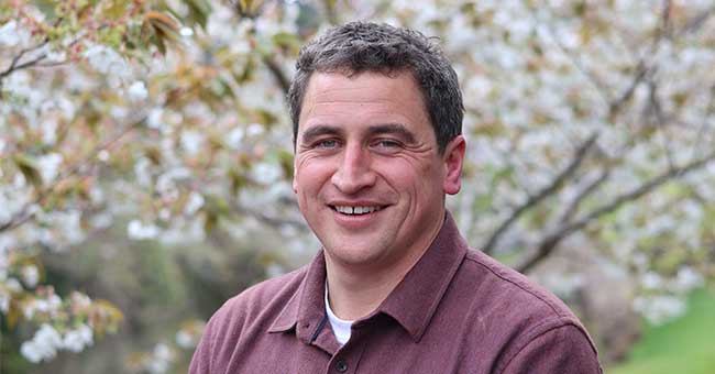 A head and shoulders of a man in front of blossom