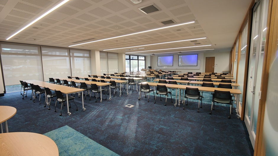 View of Otago Business School room 117, showing rows of tables and chairs