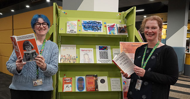Two woman stand by a display of books in the Central Library.