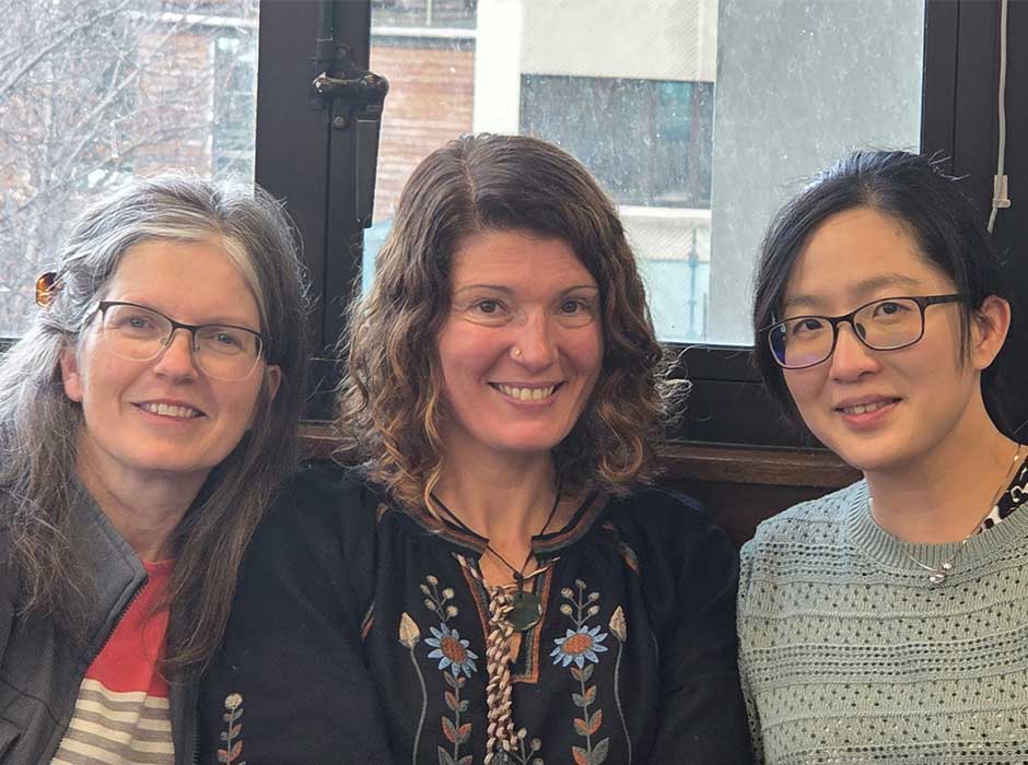 three woman seated next to each other in front of a window