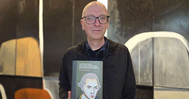 Professor Tony Ballantyne holding his new book.