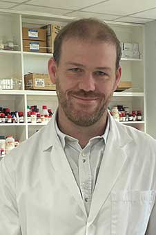 A head and shoulders of a man in a white lab coat
