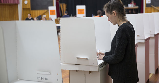 Woman casts vote at white voting booth image