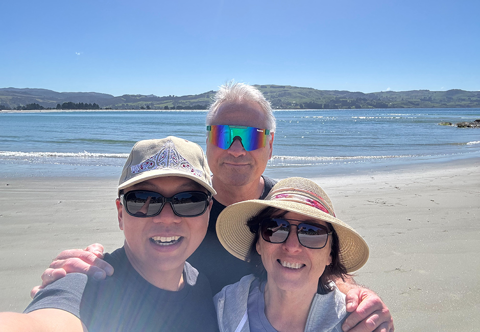 Student with homestay host family on beach.