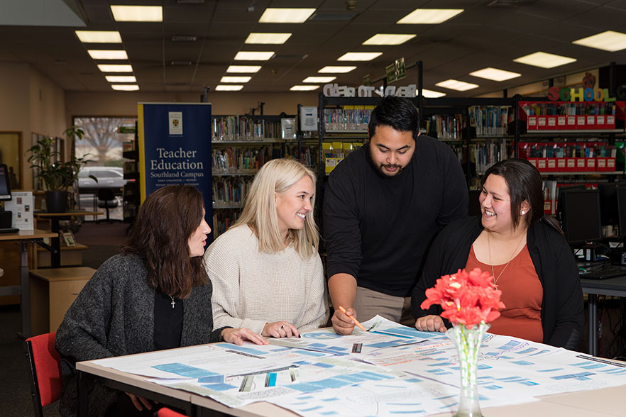 Four students working around the table in the Southland campus library