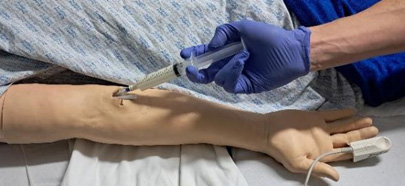 Close up on nurse injecting into prosthetic arm in a simulation setting.