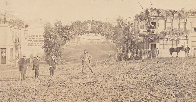 A black and white photo of the Octagon, Dunedin in 1863, a few people, lots of mud and a horse