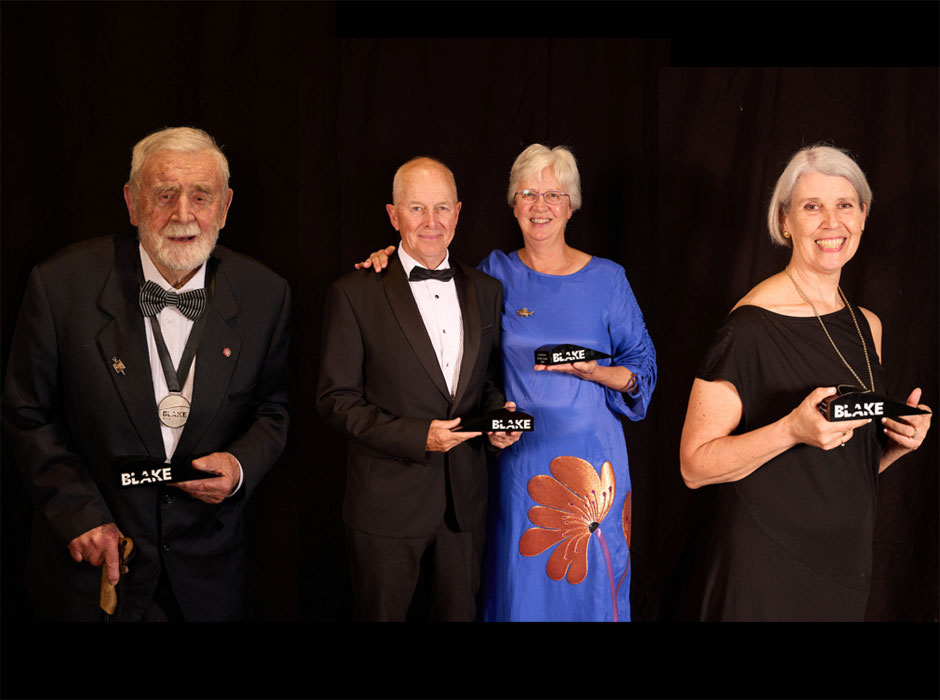 four people standing, each holding an award 