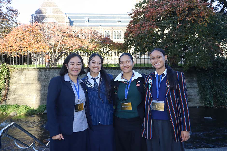 A group of female Pacific Island students in school uniforms in front of the University of Otago Clocktower