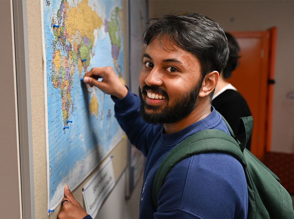 A man standing in front of a map putting a pin into it