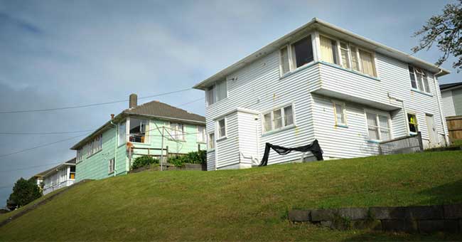 some houses on a hill top with grass around them 