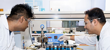 Two pharmacy students using lab equipment in the lab