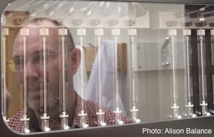 Scientist's face reflecting on the front of a DNA sequencing machine.
