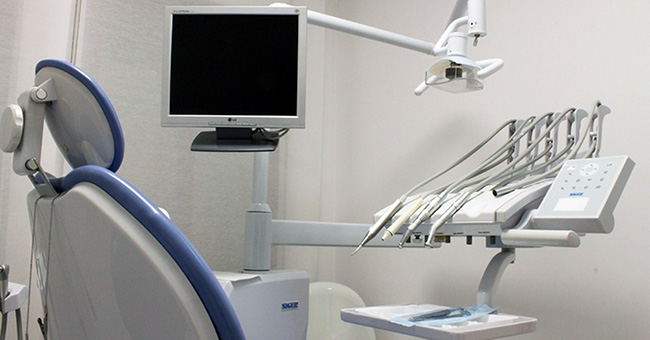 A dentist's office, with a patient's chair and other dentistry equipment
