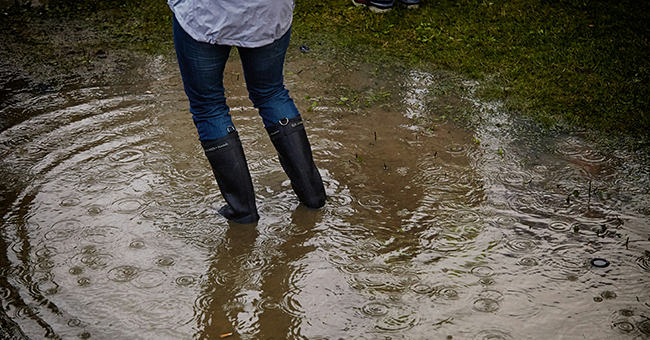 A woman standing in a puddle in gumboots