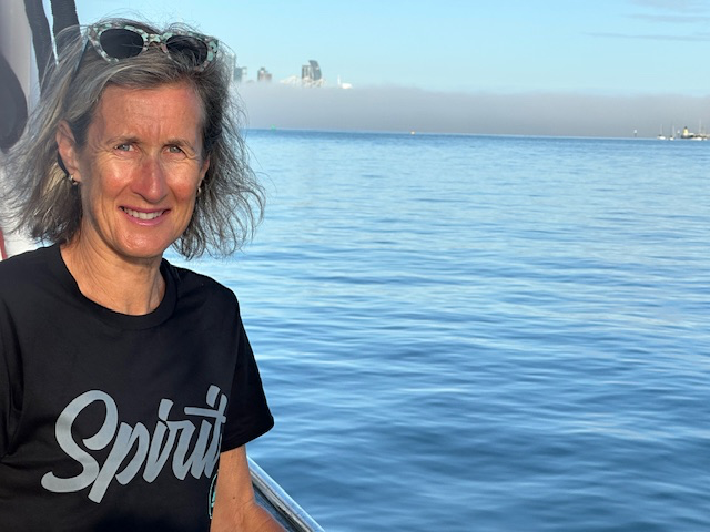 Tania Cassidy aboard a vessel in a harbour with a cityscape in the distance.