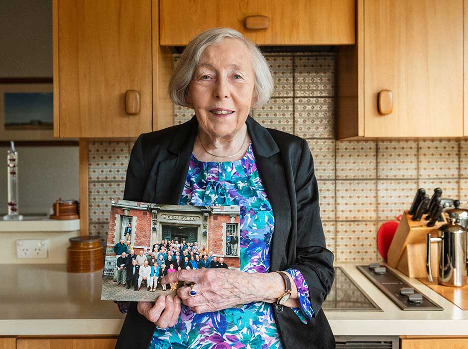 A woman standing in a kitchen holding a photo 
