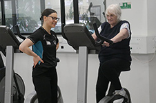 A lady on an excerise bike with a Clinical Exercise Physiology student supervising,
