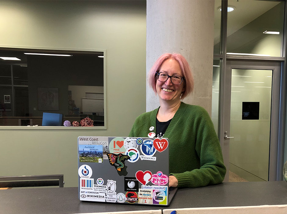 A woman standing holding a laptop 