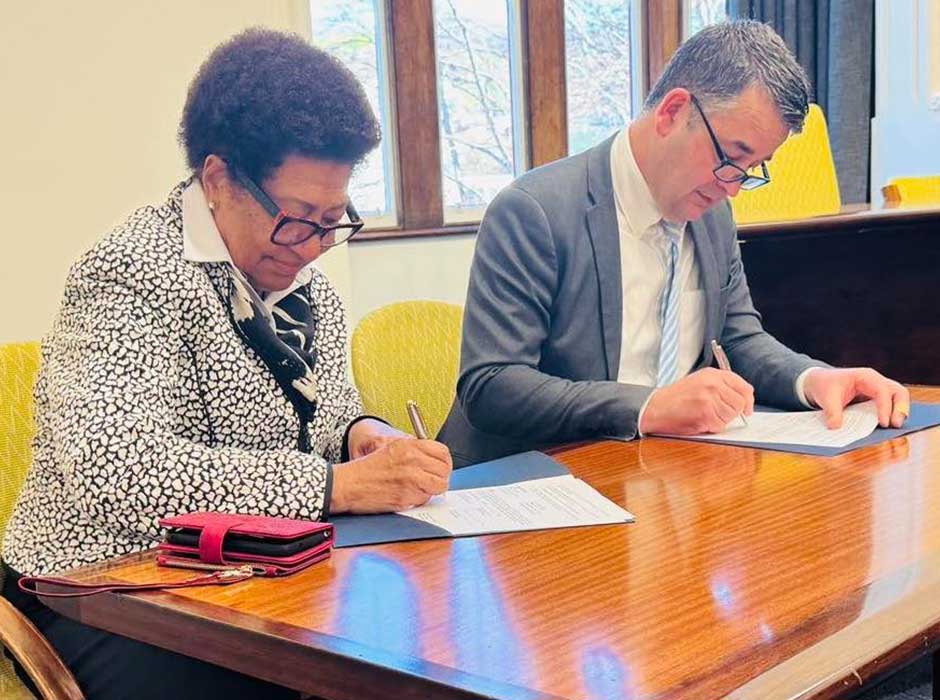 two people signing a document 
