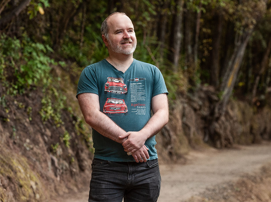 A man, standing in nature, looks happy.