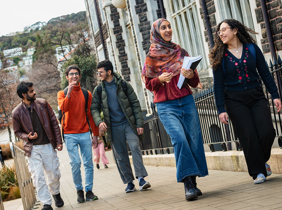 Five students walking next to each other through Otago's campus, one woman wearing a head scarf