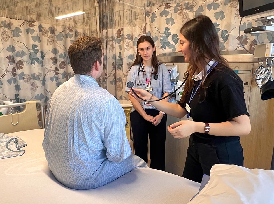 Two female medical students examine a patient