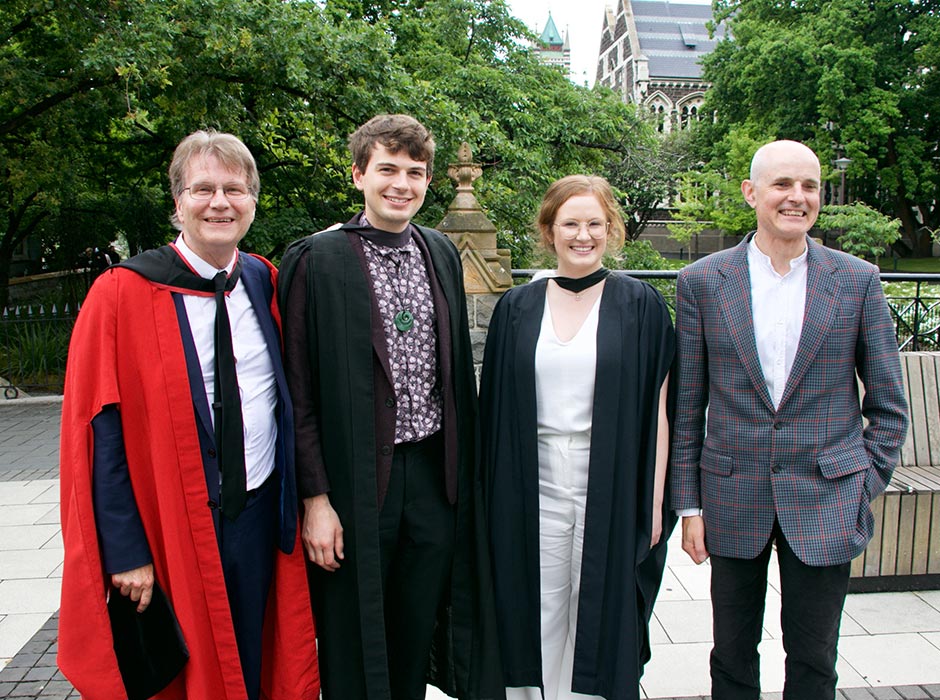 Two male professors standing with their former students.