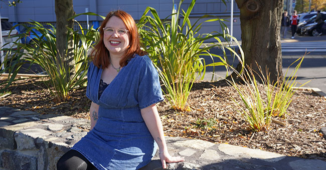 A woman posing in a garden, seated on a low wall