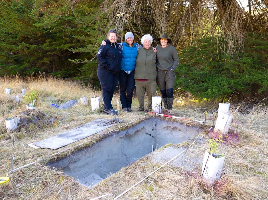 Four woman standing next to each other in front of an excavation site