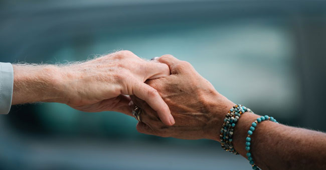 Elderly people's hands holding each other.