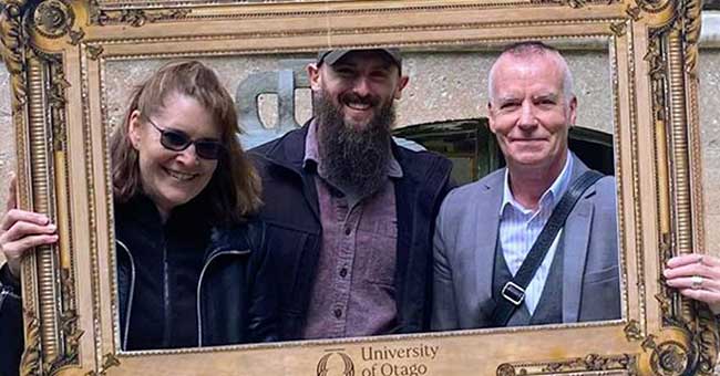 three people standing holding a cardboard fram