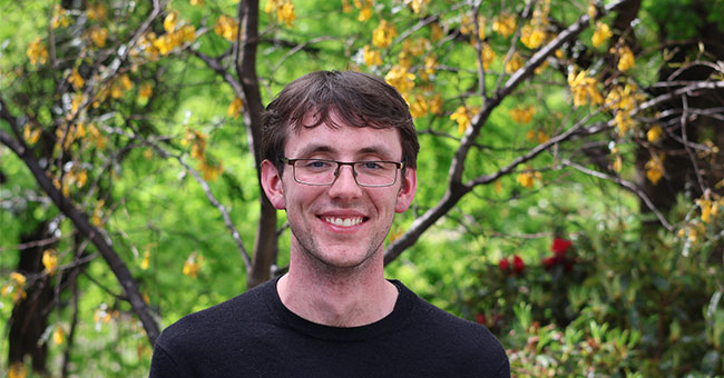 Carlo Gamble is pictured in front of greenery.