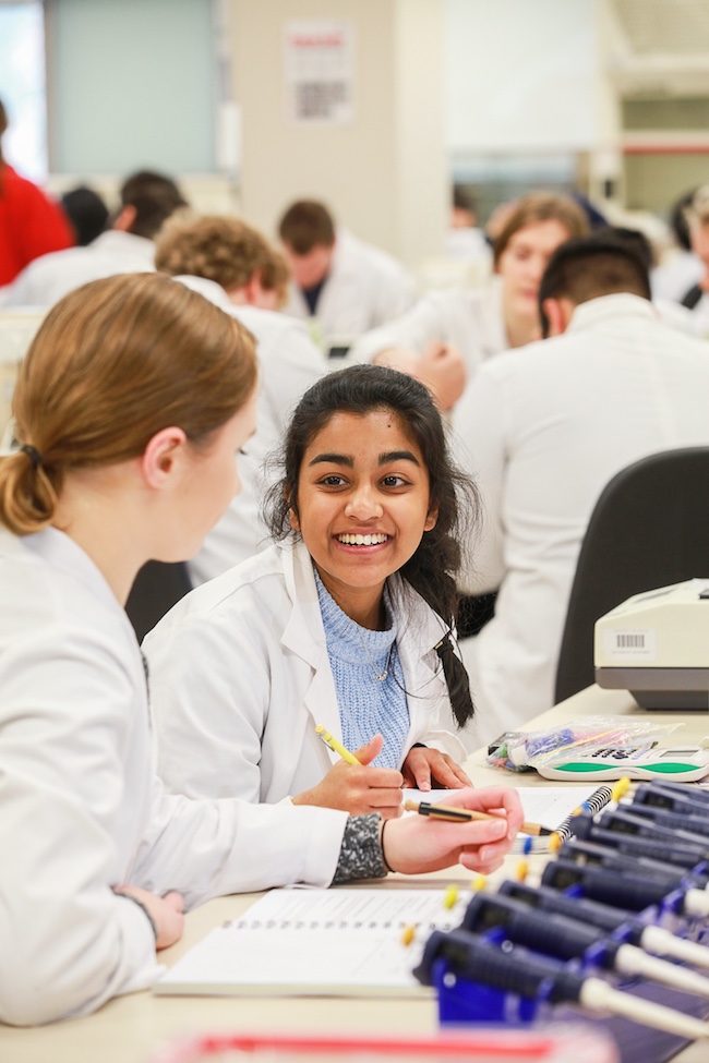 Smiling student learning about biochemistry in a lab.