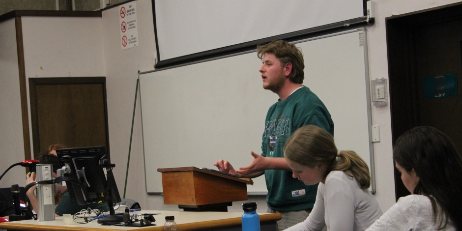 Student with mullet giving his talk in a debate.