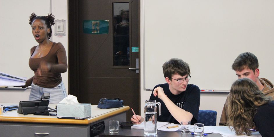 One student speaking in a debate while others have a discussion.