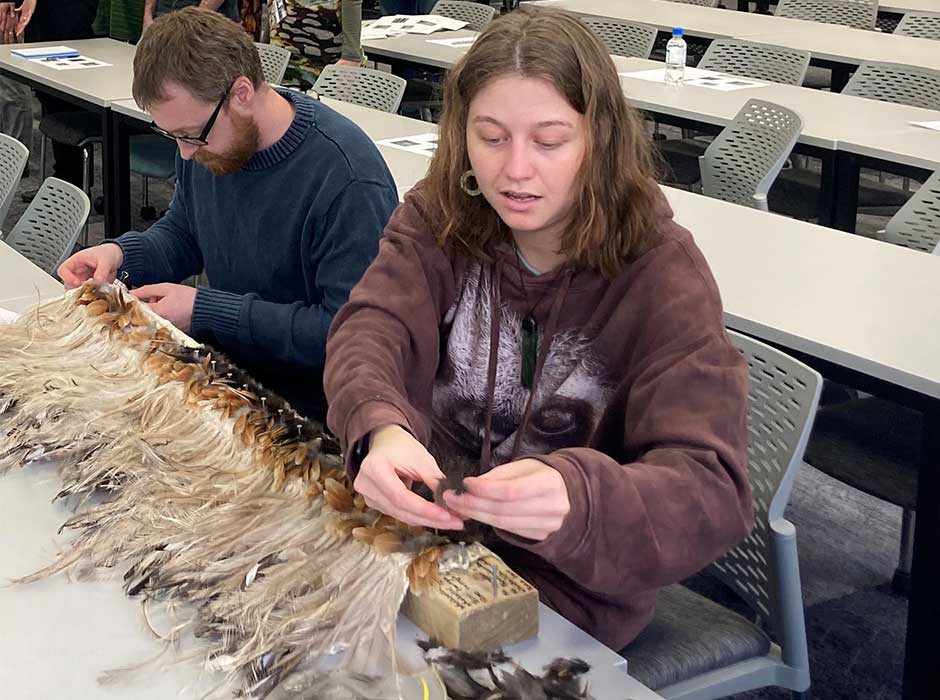 A man and a woman weaving with feathers 