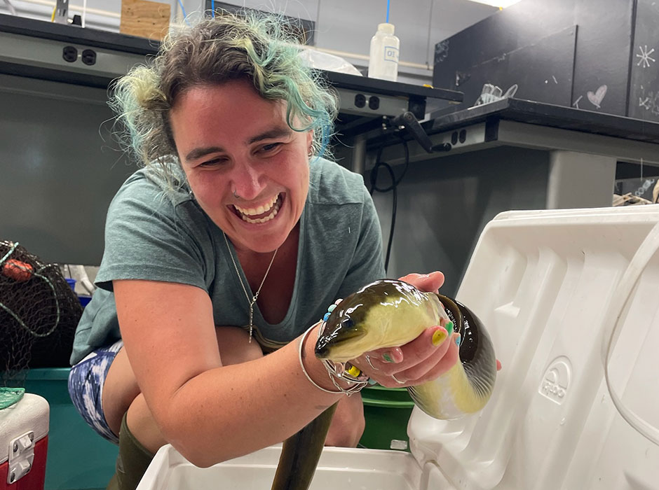 A smiling woman holding an eel 