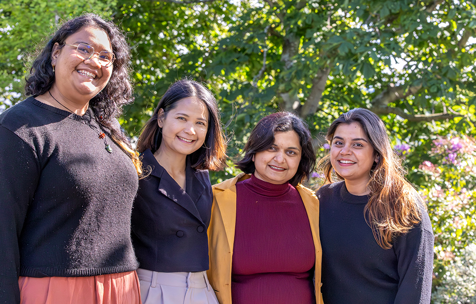 Four female students representing the 2026 PhD cohort stand in from of trees.