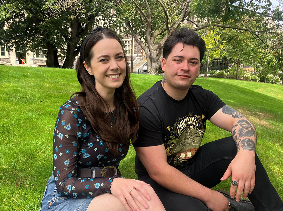Two people seated next to each other on lawn 