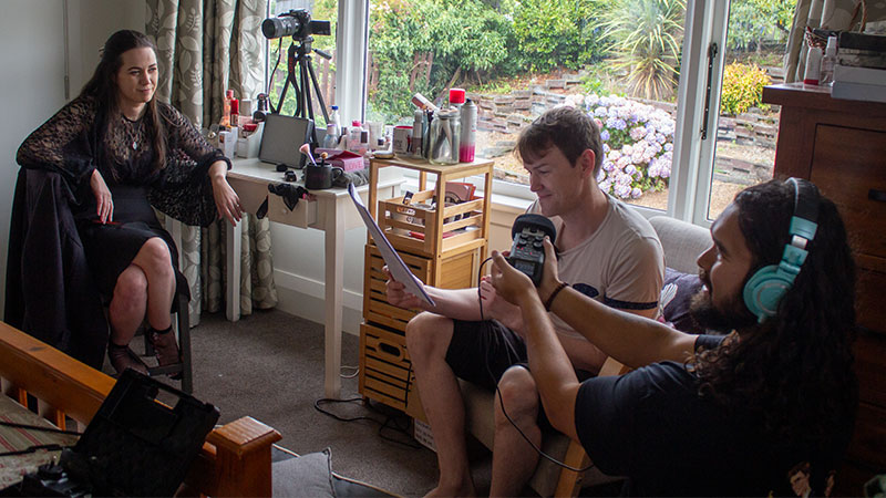 three people seated and working on a show