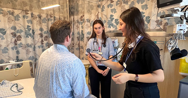 Two female medical students examine a patient