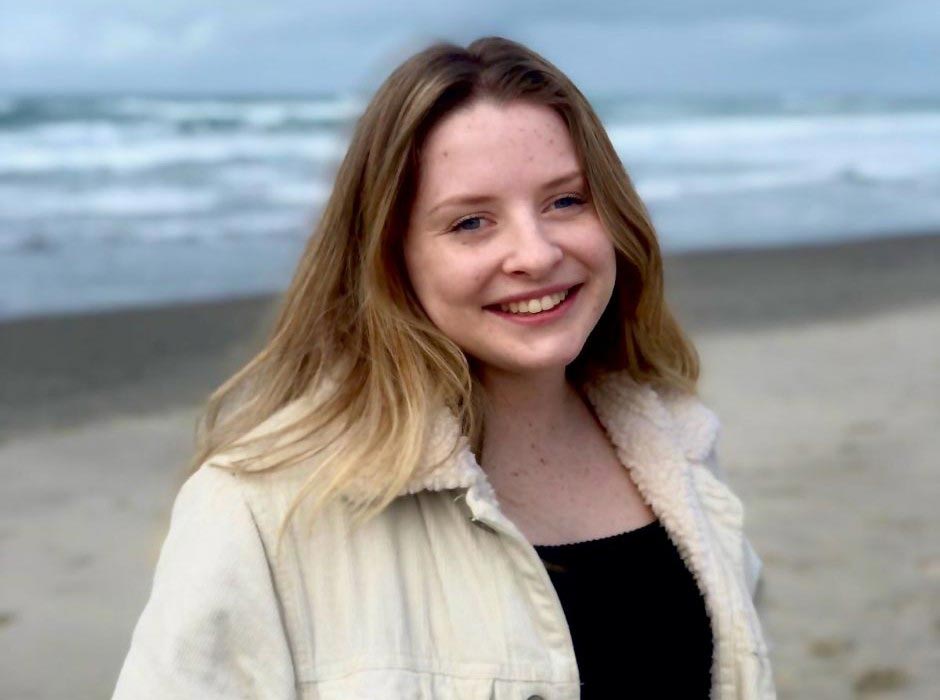 A picture of a young woman with the sea in the background.